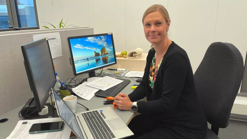 Maya sittandes vid sitt skrivbord bakom två datorskärmar