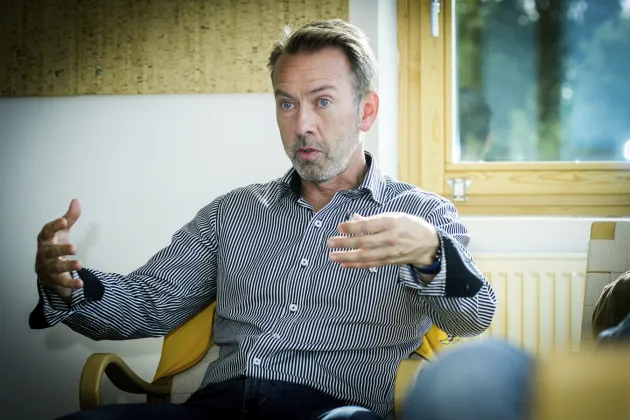 Man samtalar i fåtölj och gestikulerar med händerna.
