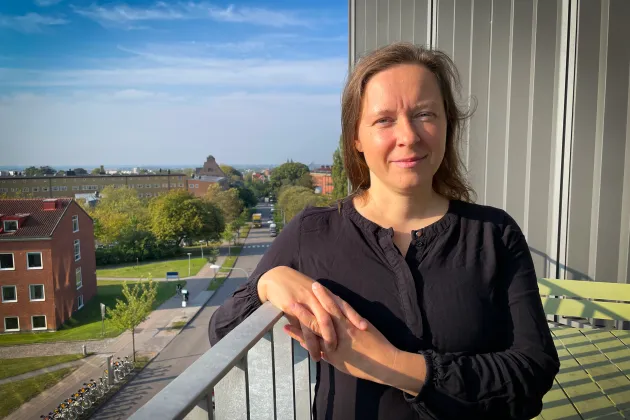 Kvinna lutar sig mot balkonräcke, Forum Medicum