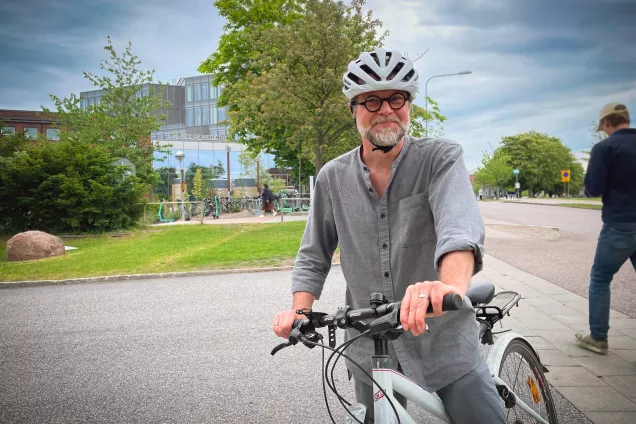 Man med cykelhjälm och en vit cykel