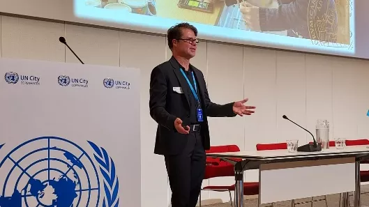 Oskar Jonsson talar vid sidan av FN-loggan.